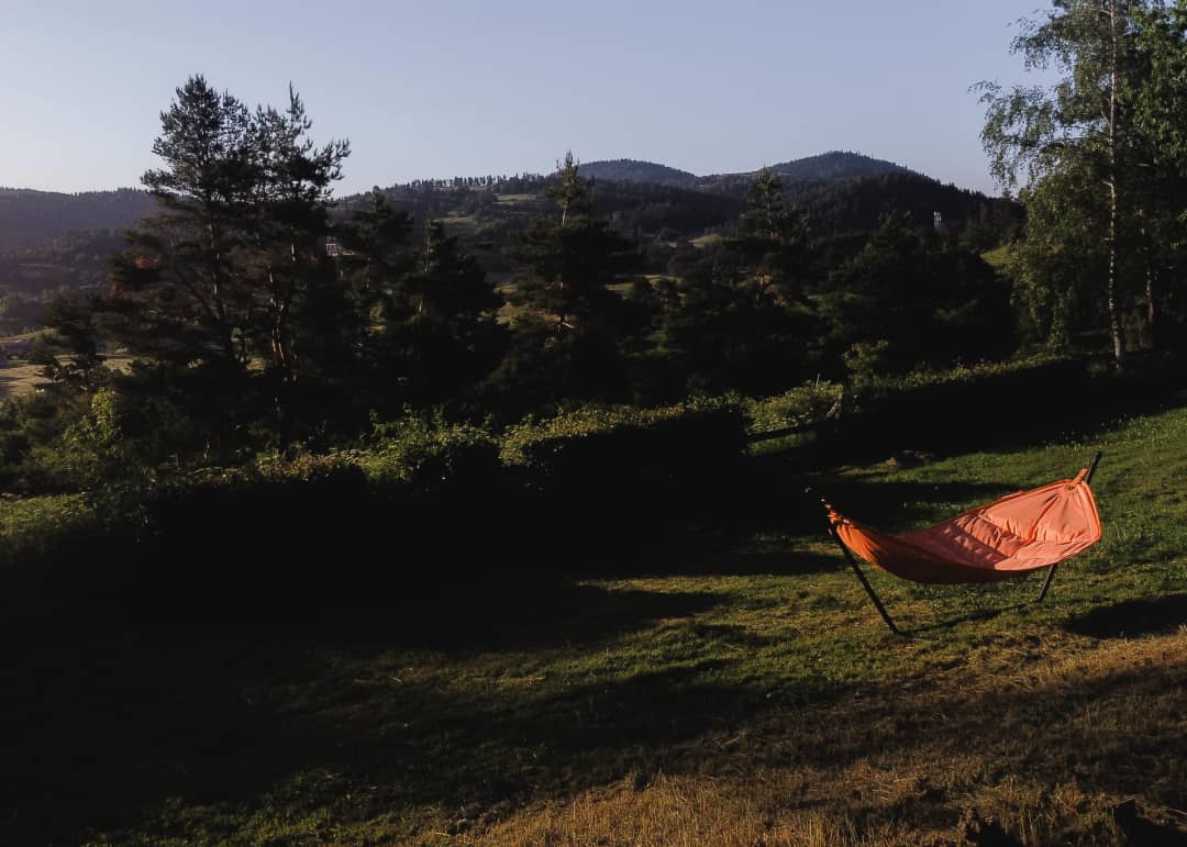 Eine Wiese mit Hängematte und Bergen im letzten Licht