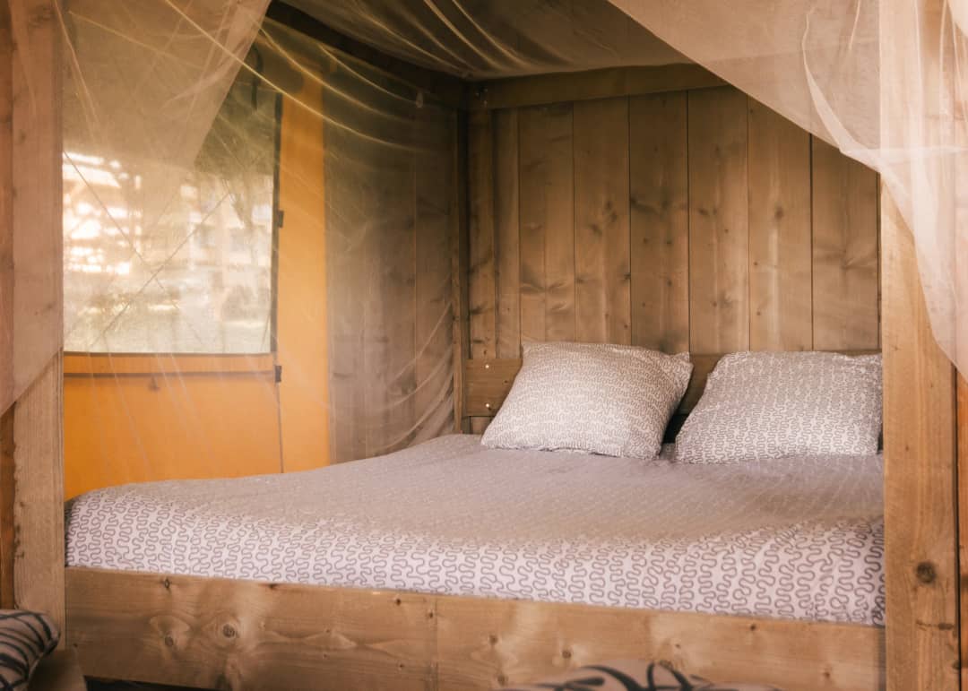 Doppelbett in der Base Lodge mit Holzwand