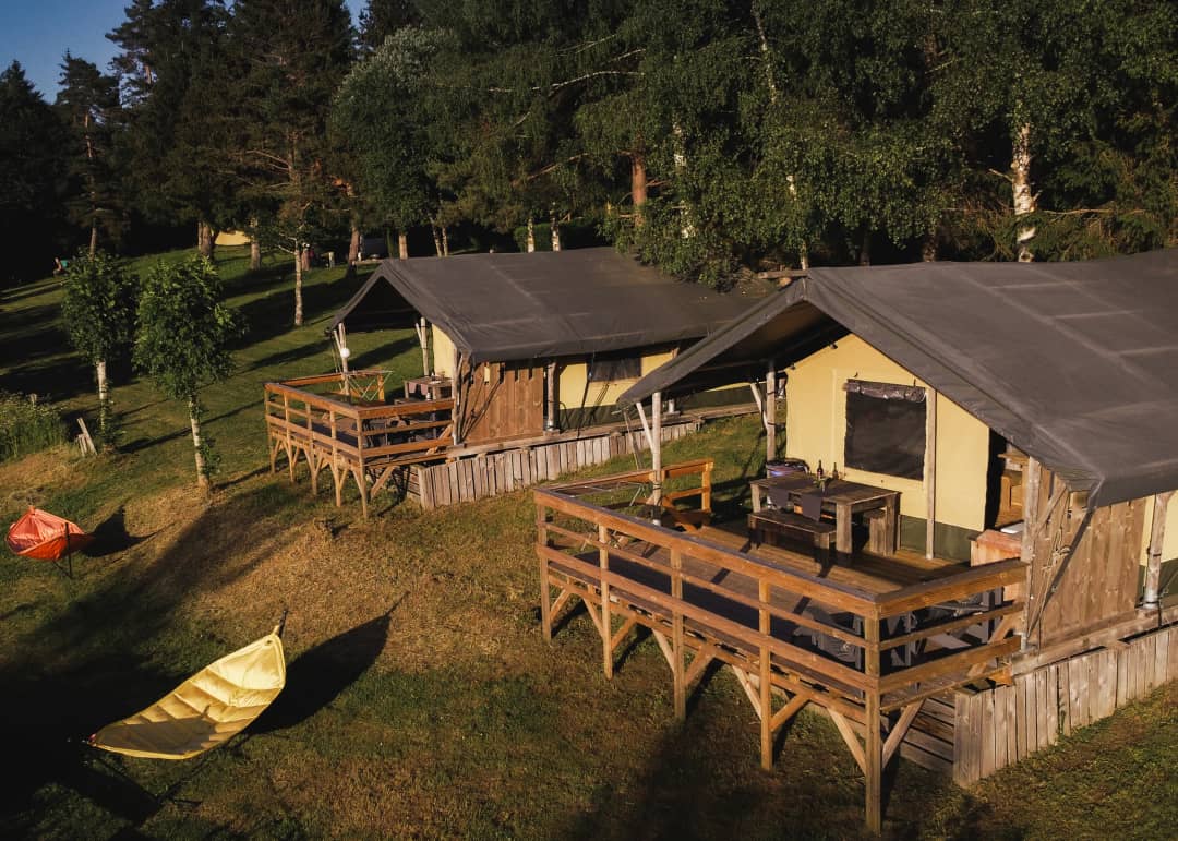 Zwei auf Pfählen stehende Base Lodges mit Terrasse in der Abendsonne in Les Sapins