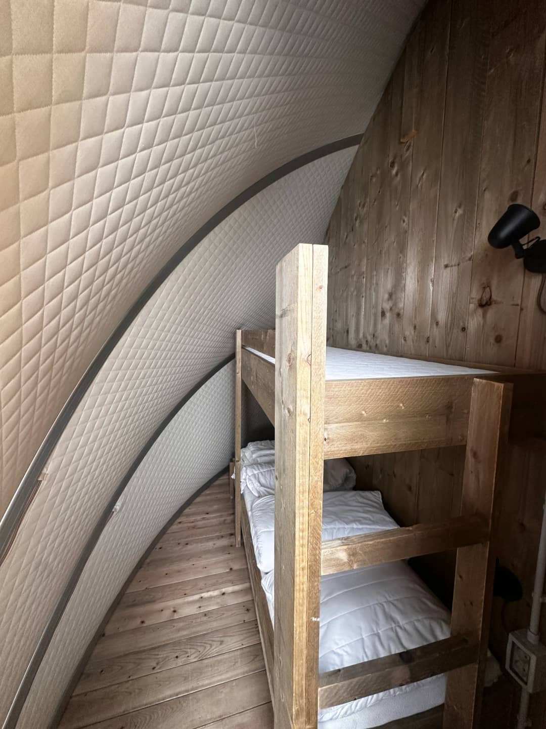 Holz-Etagenbett mit weißer Bettwäsche unter der gepolsterten, geschwungenen Wand der Big Oak Lodge XL